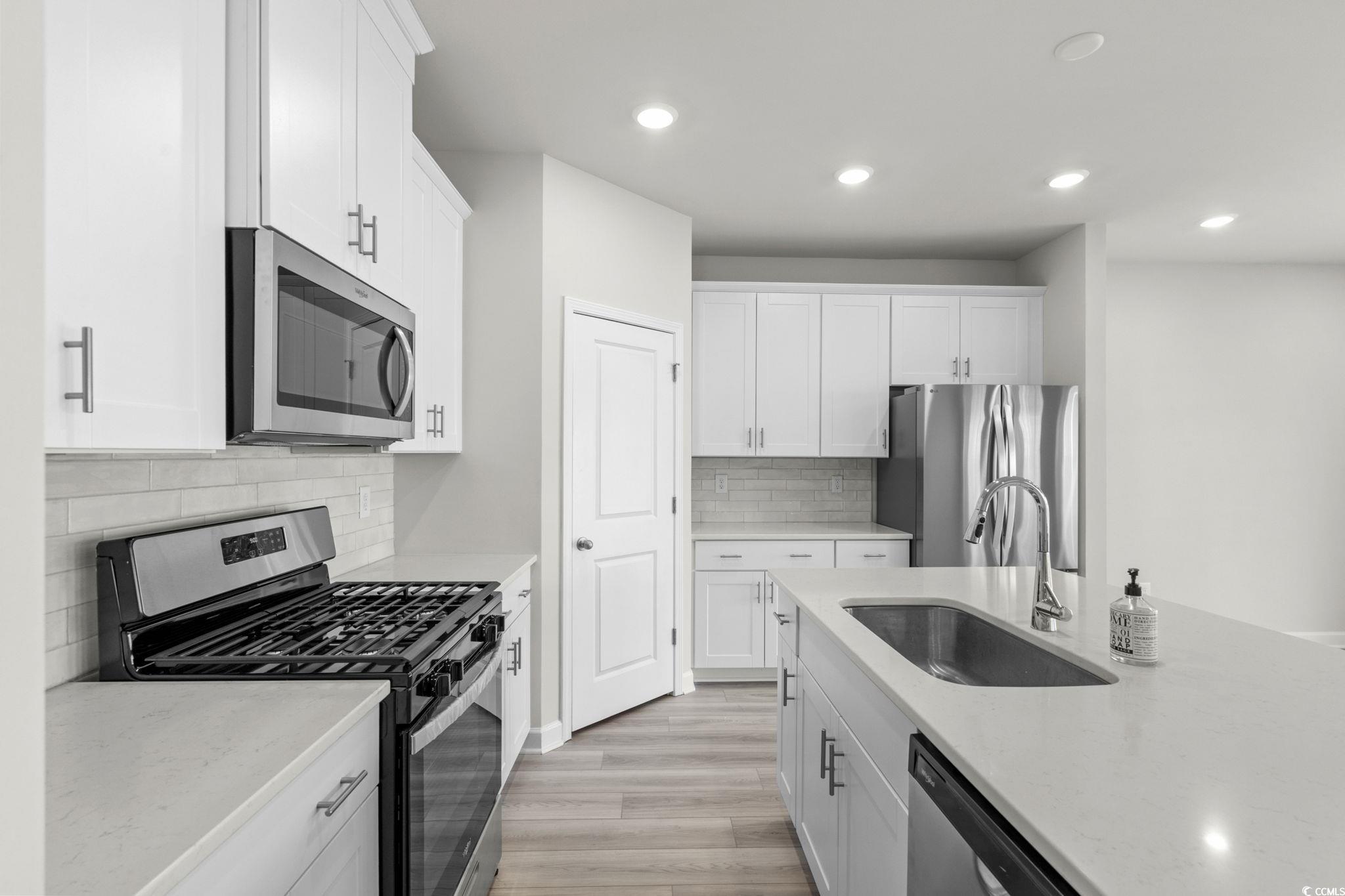 2409 Copper Crk Loop Longs, SC 29568 - Photo 7 of 40 Kitchen with stainless steel appliances, light wood-type flooring, recessed lighting, white cabinetry, and light stone counters
