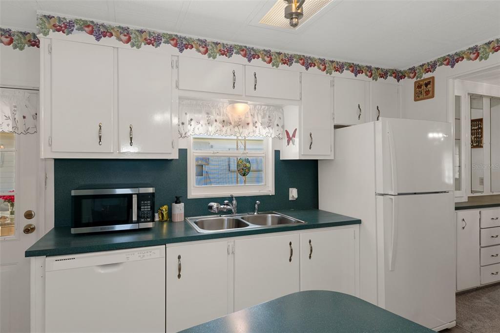 14751 Brookridge Boulevard Brooksville, FL 34613 - Photo 17 of 61 a kitchen with granite countertop a white refrigerator oven a sink dishwasher and white cabinets next to a window