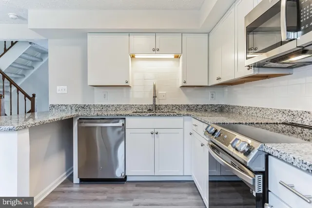 a kitchen with granite countertop cabinets stainless steel appliances and a counter space