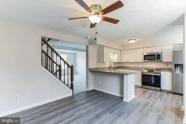 a kitchen with stainless steel appliances white cabinets and wooden floor