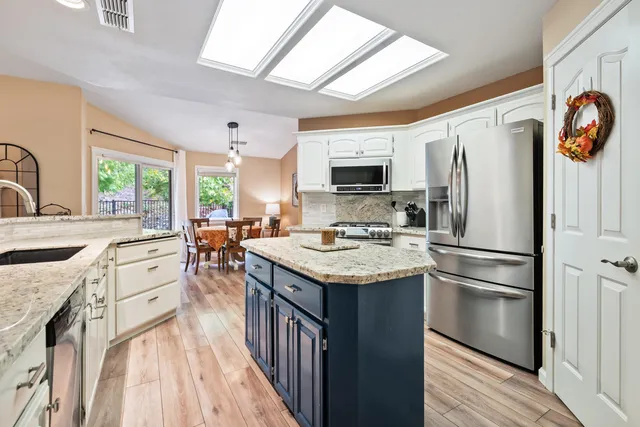 a kitchen with stainless steel appliances granite countertop a sink stove refrigerator and a window
