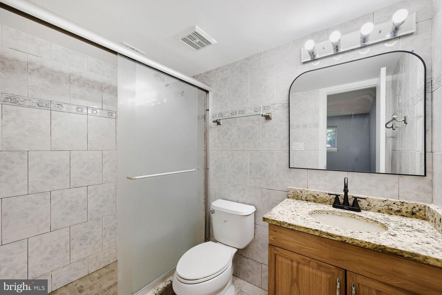 3 Windblown Court, Unit 102 Baltimore, MD 21209 - Photo 8 of 11 a bathroom with a granite countertop sink toilet and shower