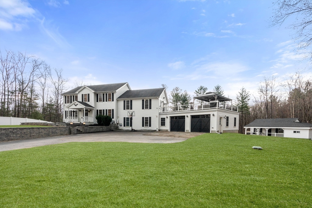 2 Britlees Way Dudley, MA 01571 - Photo 2 of 40 a front view of a house with a garden and trees
