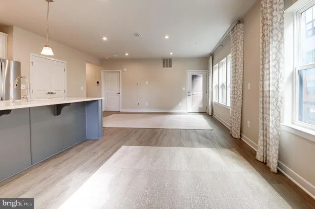 a view of a kitchen with kitchen island a sink wooden floor and a large window
