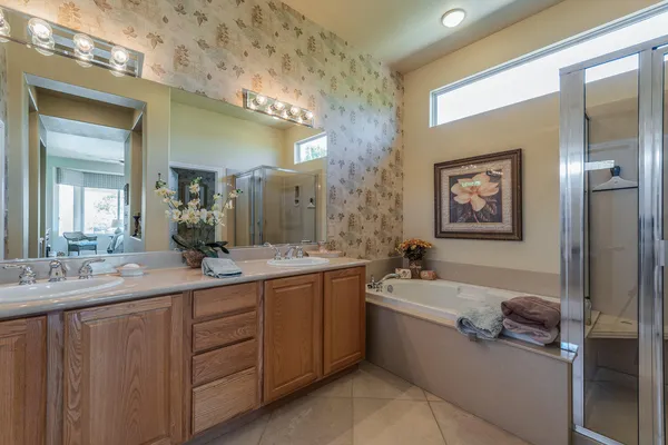 a en suite bathroom with a double vanity sink a mirror and a bathtub