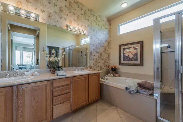 a en suite bathroom with a double vanity sink a mirror and a bathtub