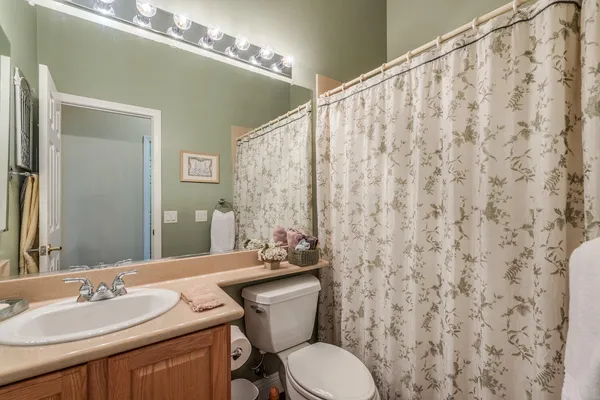 a bathroom with a granite countertop toilet sink and mirror