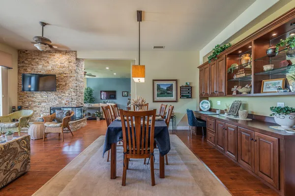 a view of a dining room and livingroom with furniture wooden floor a rug a fireplace and a chandelier