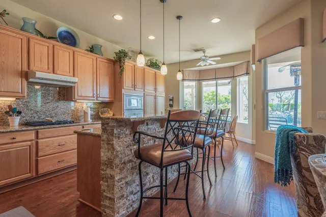 a kitchen with stainless steel appliances granite countertop a table chairs sink and wooden floor