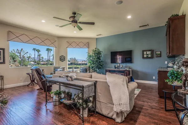 a living room with furniture a flat screen tv and a refrigerator