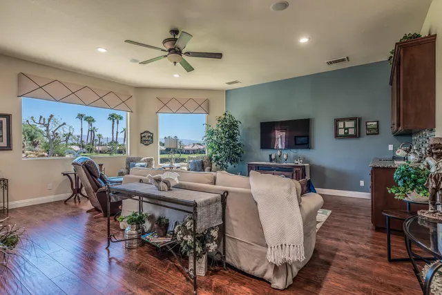 a living room with furniture a flat screen tv and a refrigerator