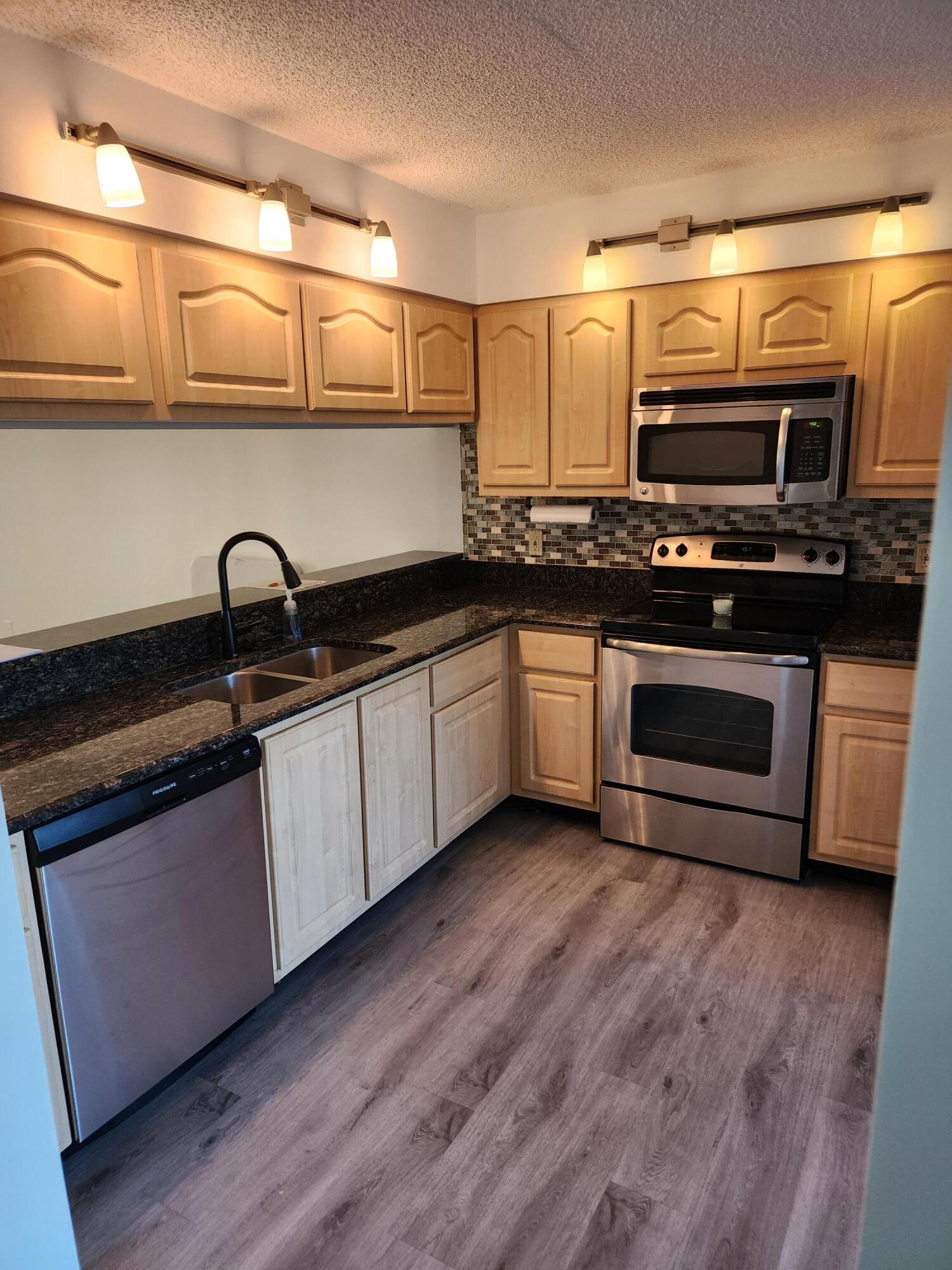 6263 Riverwalk Lane, Unit 2 Jupiter, FL 33458 - Photo 2 of 44 a kitchen with stainless steel appliances granite countertop a sink a stove a microwave and wooden floors