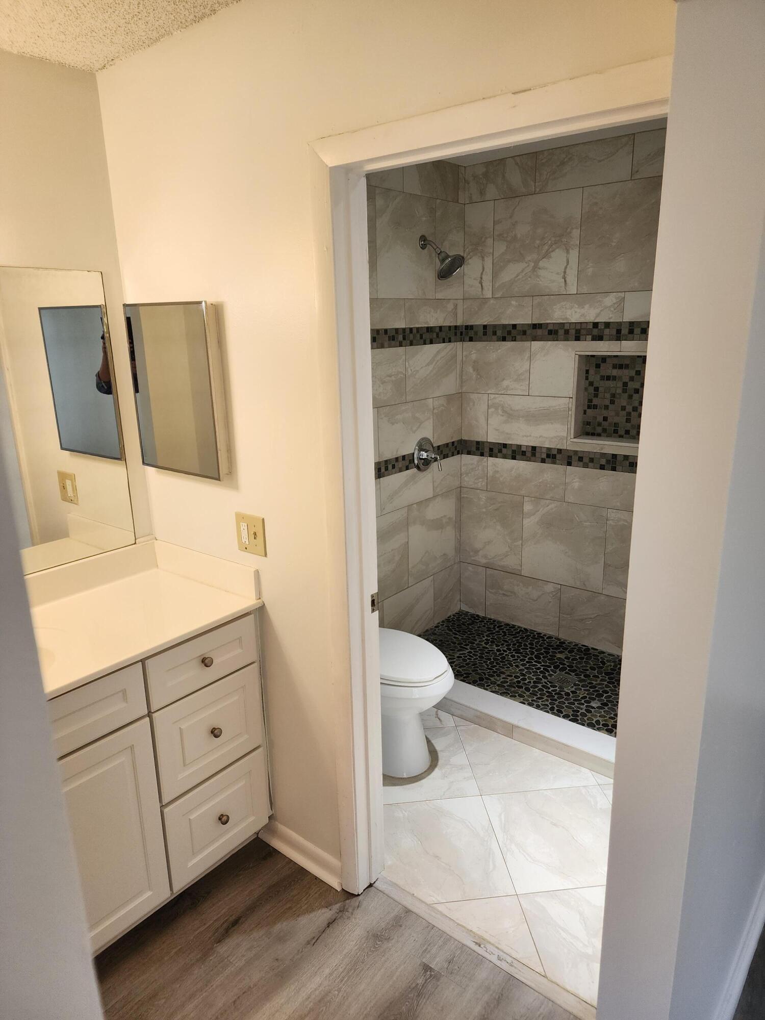 6263 Riverwalk Lane, Unit 2 Jupiter, FL 33458 - Photo 31 of 44 a bathroom with a granite countertop sink a toilet and shower