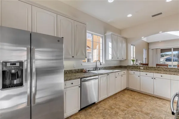 a kitchen with granite countertop sink a window and cabinets