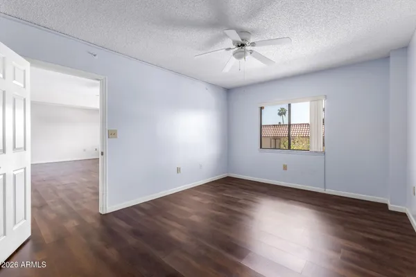 an empty room with wooden floor chandelier fan and windows