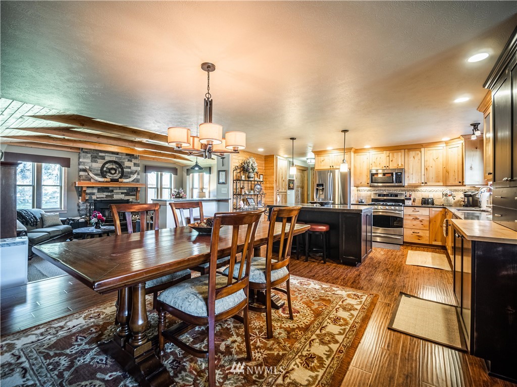 39 Cape Labelle Road Tonasket, WA 98855 - Photo 2 of 39 an open kitchen with granite countertop a stove a sink a dining table and chairs with wooden floor