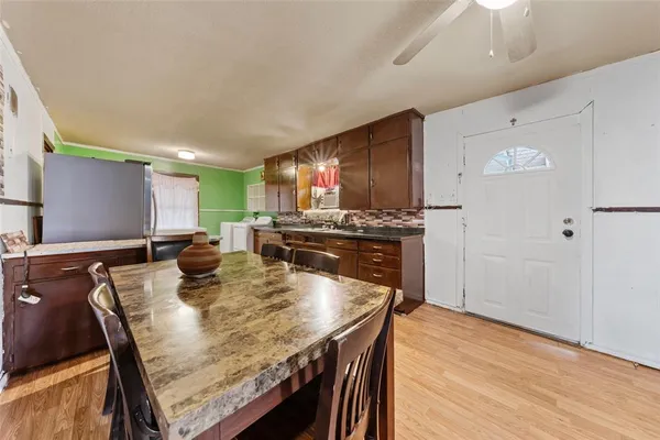 a kitchen with stainless steel appliances granite countertop a stove a refrigerator a microwave oven with white cabinets and wooden floor