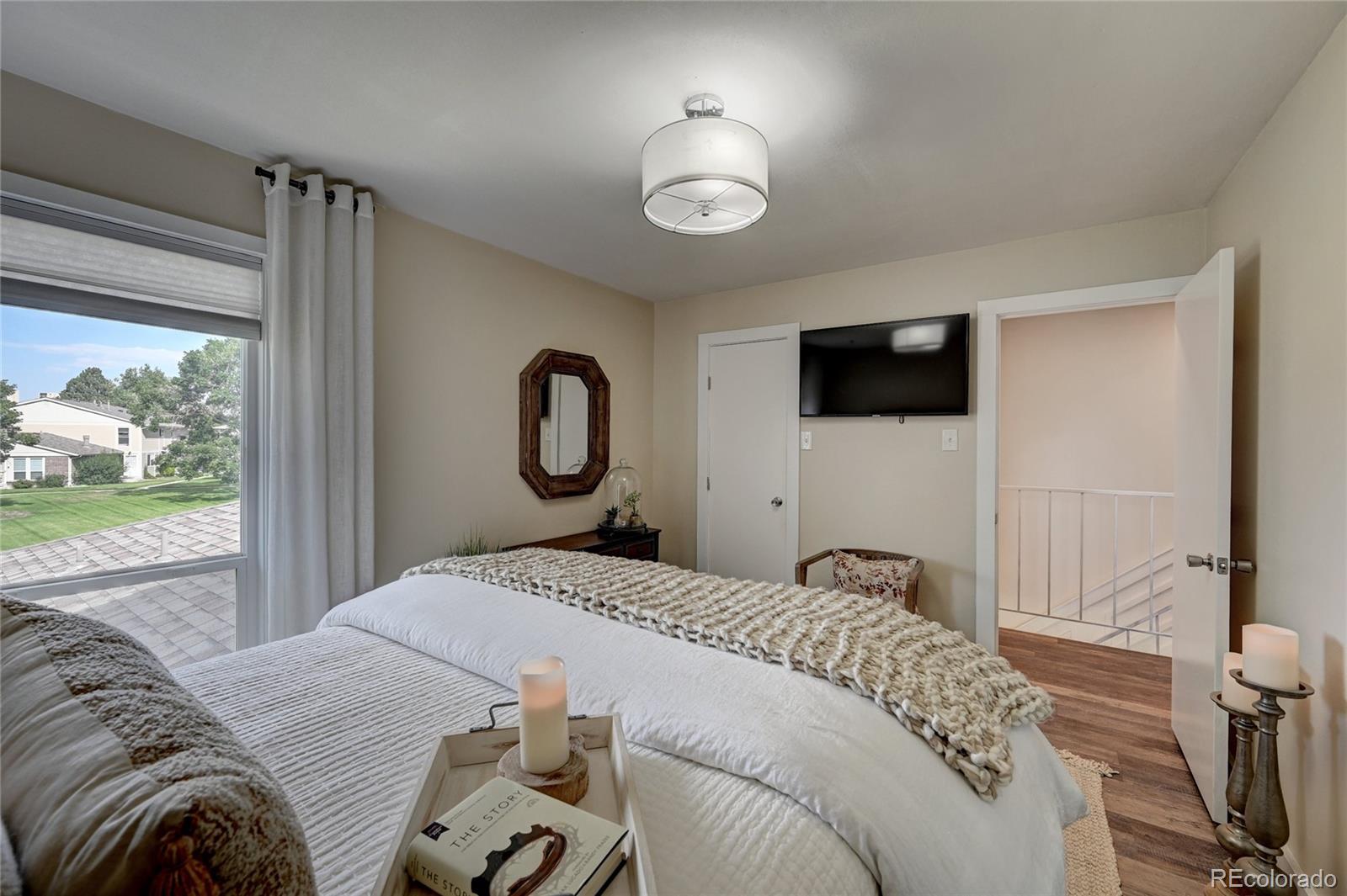 1225 South Oneida Street, Unit 219 Denver, CO 80224 - Photo 16 of 25 a bedroom with a bed and a flat tv screen next to a window