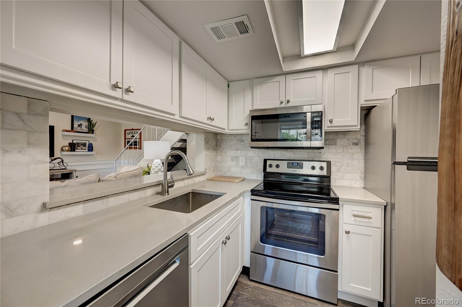 1225 South Oneida Street, Unit 219 Denver, CO 80224 - Photo 9 of 25 a kitchen with white cabinets and stainless steel appliances