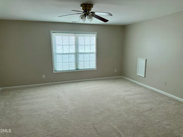 an empty room with a ceiling fan and windows