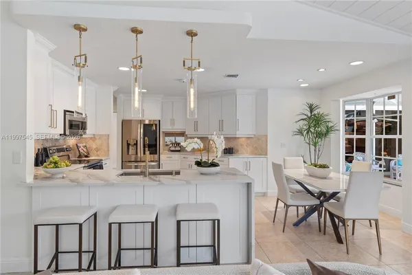 a kitchen with stainless steel appliances kitchen island granite countertop a table chairs and a refrigerator