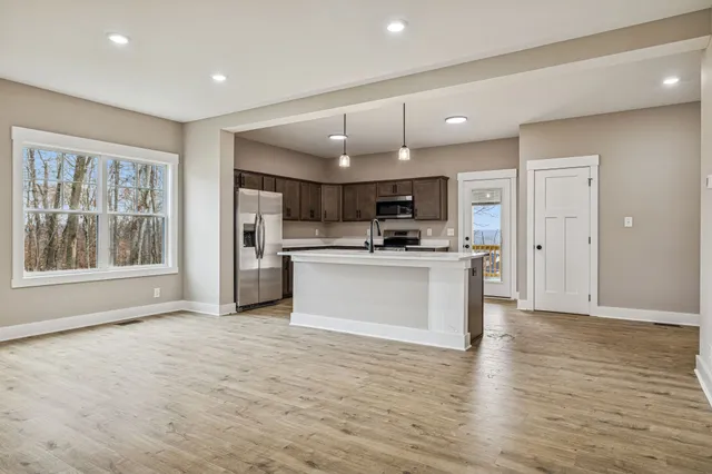 a large kitchen with cabinets wooden floor and stainless steel appliances