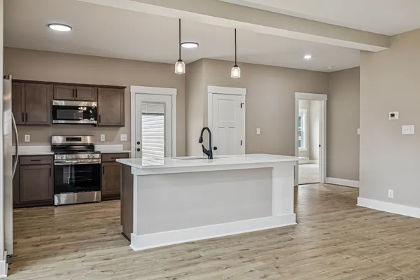 a large kitchen with stainless steel appliances granite countertop a sink a counter space and wooden floor