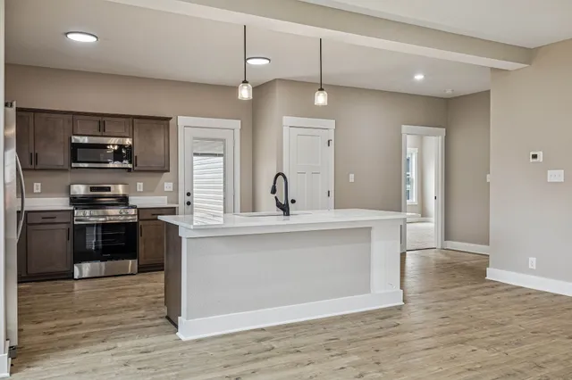a large kitchen with stainless steel appliances granite countertop a sink a counter space and wooden floor