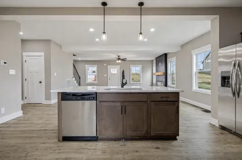 a large kitchen with stainless steel appliances granite countertop a sink a counter space and wooden floor