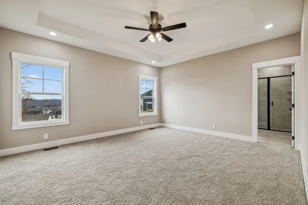 an empty room with chandelier fan and windows