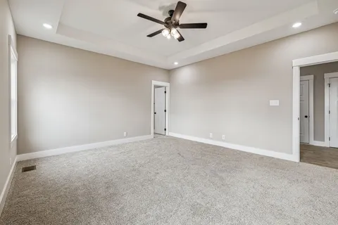 an empty room with chandelier fan and windows
