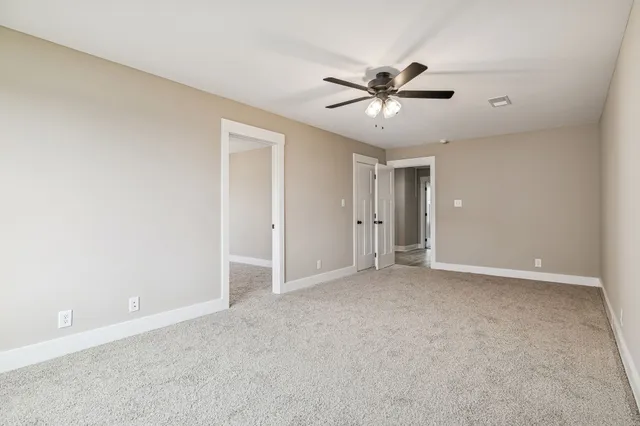 an empty room with ceiling fan and windows
