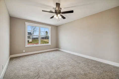 an empty room with ceiling fan and windows