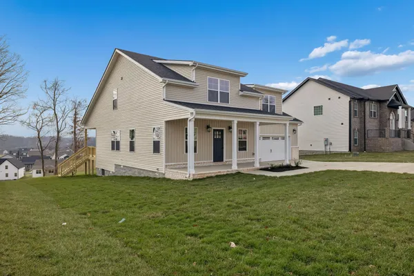 a view of a white house with a big yard and large trees