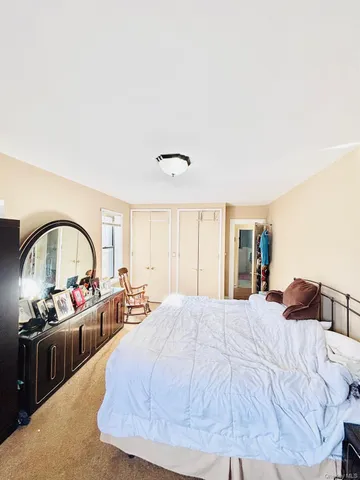 a spacious bedroom with a bed and a large mirror on dresser