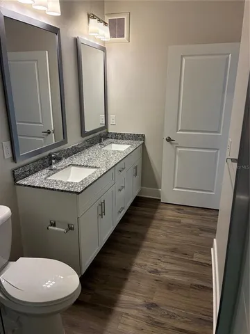 a bathroom with a granite countertop toilet sink and mirror