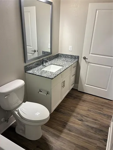 a bathroom with a granite countertop toilet and a sink