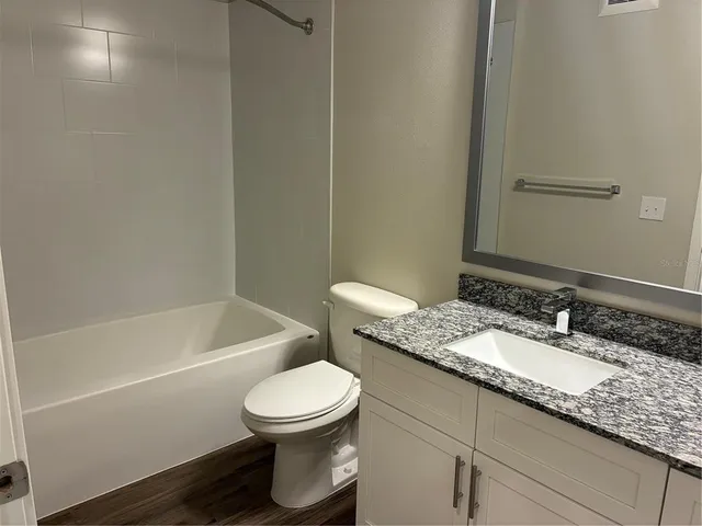a bathroom with a granite countertop sink a toilet and bathtub
