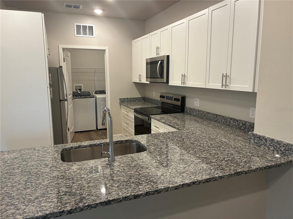2115 Waterfall Ct Mount, Unit 8211 Mount Dora, FL 32757 - Photo 7 of 21 a kitchen with stainless steel appliances granite countertop a sink a stove and a microwave