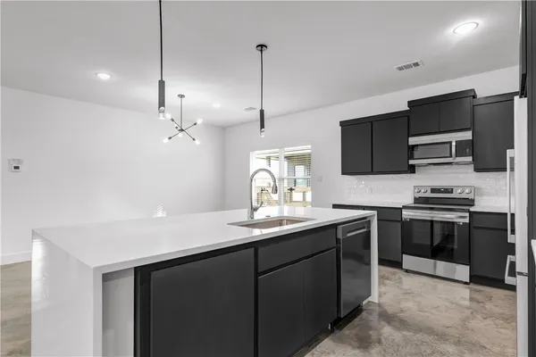 a kitchen with stainless steel appliances granite countertop a sink a stove a oven a refrigerator with grey walls and cabinets