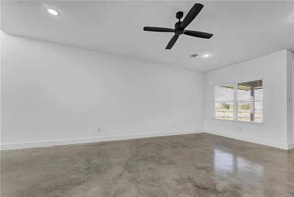 an empty room with ceiling fan and windows