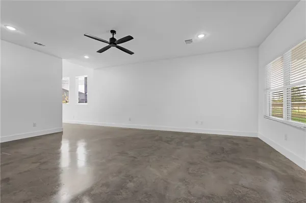 an empty room with wooden floor ceiling fan and windows