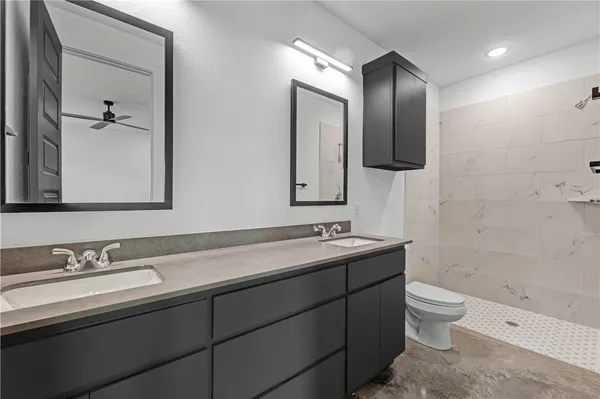 a bathroom with a double vanity sink toilet mirror and shower