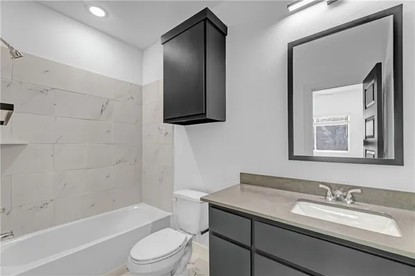 a bathroom with a granite countertop sink toilet a mirror and bathtub