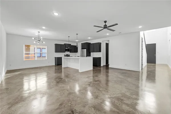 a view of a kitchen with a sink a refrigerator a ceiling fan and wooden floor