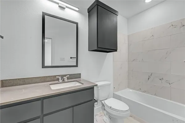 a bathroom with a toilet a sink a mirror a bathtub and vanity