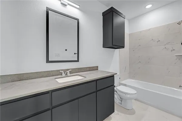 a bathroom with a granite countertop toilet sink and mirror