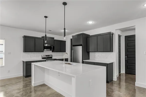 a kitchen with stainless steel appliances kitchen island granite countertop a sink a microwave a refrigerator and a stove