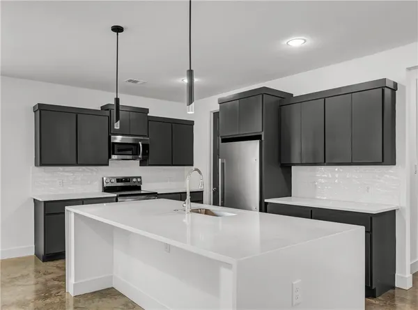 a kitchen with stainless steel appliances a refrigerator a sink a stove a microwave and island