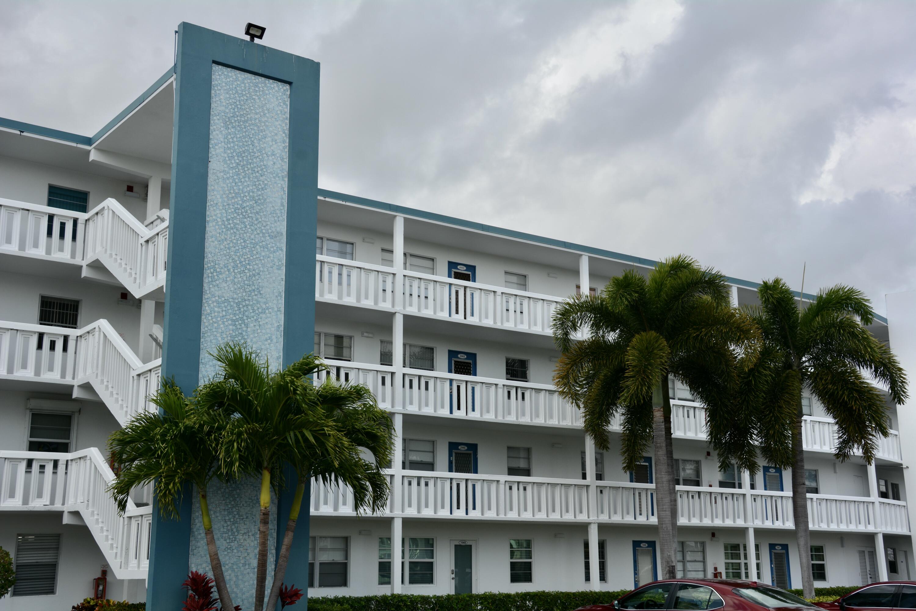 a front view of a building with palm trees